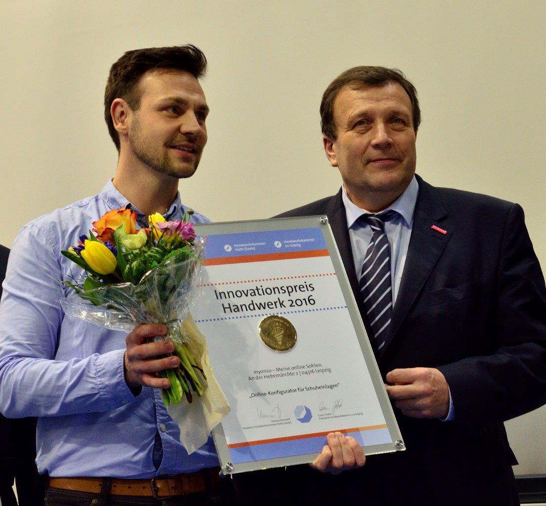 Christoph Mätzold steht neben Volker Lux dem Geschäftsführer der Handwerkskammer zu Leipzig. In der einen Hand hält Herr Mätzold einen Strauß Blumen und in der anderen das Zertifikat für den Innovationspreis im Handwerk 2016.